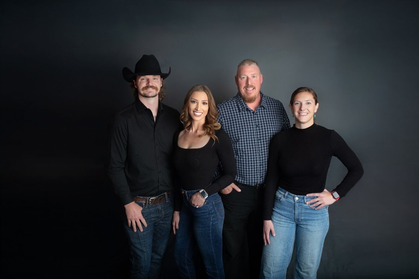 Four people standing together against a dark studio backdrop